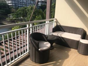 a balcony with two wicker chairs and a table at Creys condo at Pico de Loro Cove in Nasugbu
