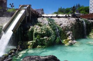 uma cascata junto a uma piscina de água em Kusatsu Onsen Guesthouse Gyoten em Kusatsu