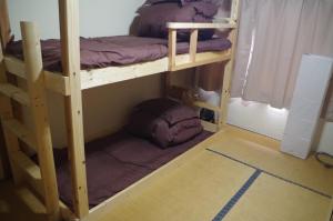 two bunk beds in a room with a floor at Kusatsu Onsen Guesthouse Gyoten in Kusatsu