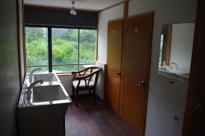 ein Bad mit einem Waschbecken und ein Fenster mit einem Stuhl in der Unterkunft Kusatsu Onsen Guesthouse Gyoten in Kusatsu