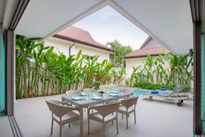 a patio with a table and chairs and a pool at Villa Karina in Rawai Beach