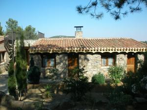 a small stone house with a tile roof at La Quinta de los Enebrales in Hoyo de Pinares