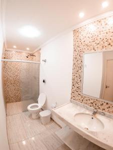Un baño con inodoro, lavabo y espejo. en Flat Apart Hotel Marinas Tamandaré, en Tamandaré