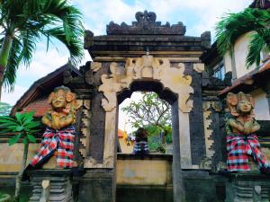 a building with two statues on it with palm trees at Pande Permai Bungalows in Ubud