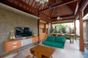 ein Wohnzimmer mit einem grünen Sofa und einem Fernseher in der Unterkunft Villa Niketan Sanur - Three bedroom, Sanur, Near Icon Mall, Harbor in Sanur
