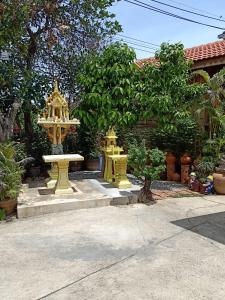 een tuin met twee gele standbeelden en een fontein bij J&J Guesthouse in Sukhothai