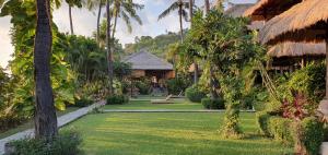un jardín con palmeras y un complejo en Coral View Villas, en Amed