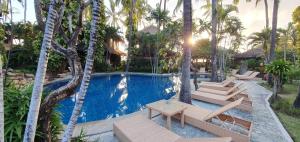 a resort swimming pool with lounge chairs and palm trees at Coral View Villas in Amed