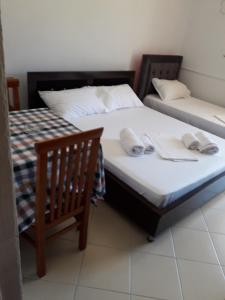 two twin beds in a room with two chairs at Guesthouse Emanuel in Ksamil