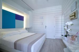a white bedroom with a large bed and a table at Hotel Helen in Caorle