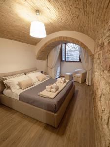a bedroom with a large bed with a stone wall at Residenza Porta Perlici Assisi Apartment in Assisi