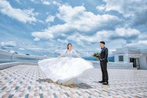 Una novia y un novio parados en el techo de un edificio en Hoang Nham Luxury Hotel, en Ta Lan Than