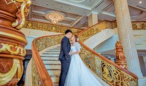 Une mariée et un marié marchent par un escalier. dans l'établissement Hoang Nham Luxury Hotel, à Ta Lan Than
