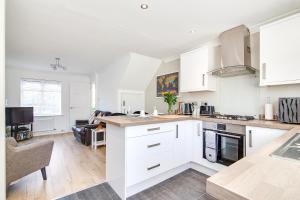 uma cozinha com armários brancos e uma sala de estar em Westmorland House em Tamworth