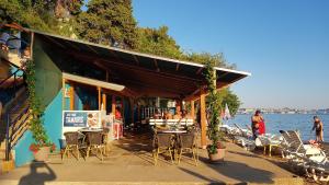 a restaurant with tables and chairs next to the water at Apartmani Maver in Sveti Filip i Jakov