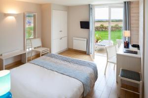 a bedroom with a bed and a desk and a window at Logis Hôtel Vent d'Iroise in Plougonvelin