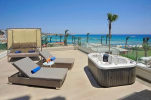 a hot tub and chairs on a balcony with the beach at Nelia Beach Hotel & Spa in Ayia Napa