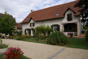 a white house with a red roof and some flowers at Chambres d'Hôtes Domaine d'Augy in Farges-en-Septaine