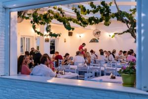 un grupo de personas sentadas en mesas en un restaurante en Pavlos Place, en Antíparos