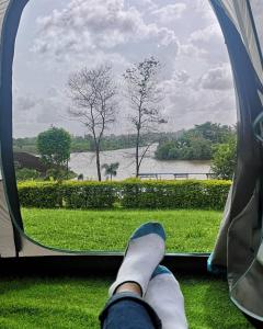 a persons feet looking out a window at a lake at Campistaan Karjat in Karjat