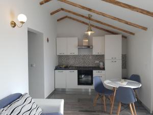 a kitchen with white cabinets and a table and chairs at Apartmani Dalmatinka in Metajna