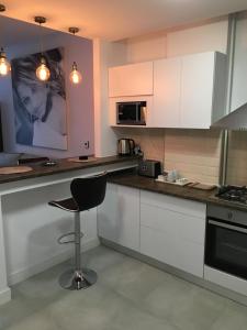 une cuisine avec des placards blancs et une chaise noire dans l'établissement Adams Apartment Onix Blue, à Mamaia Nord – Năvodari