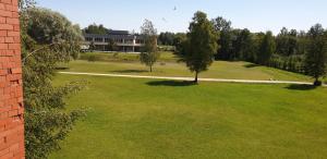 a large green field with trees and a building at Apartamenti Danna in Lēdmane