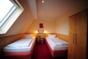 2 Betten in einem kleinen Zimmer mit Fenster in der Unterkunft Gasthof Löwen GmbH in Heitersheim