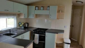 uma cozinha com armários brancos e um forno de fogão preto em Pine Ridge 59 Rockley Park Poole with sea view sleeps six em Poole