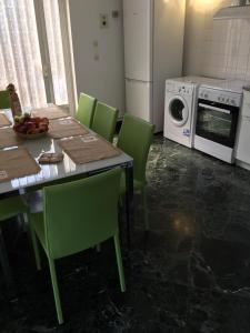 a kitchen with a table and green chairs and a microwave at Turtle harbour Seafront Apartment! Full Seaview!!! in Argostoli