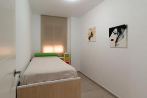 a small bedroom with a bed and two pictures on the wall at Bioparc Metro Valencia in Valencia