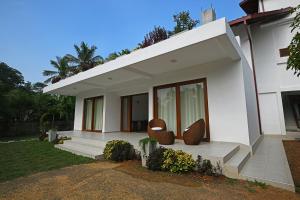 Casa blanca con 2 sillas en el porche delantero en Colibri Villa, en Maggona West