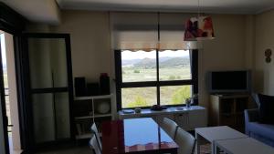 un salon avec une grande fenêtre et une télévision dans l'établissement Apartamento en playa de Almenara con vistas a la Marjal, à Almenara
