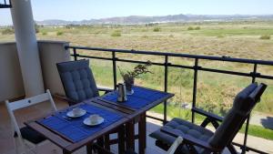 d'une table et de chaises sur un balcon avec vue sur un champ. dans l'établissement Apartamento en playa de Almenara con vistas a la Marjal, à Almenara