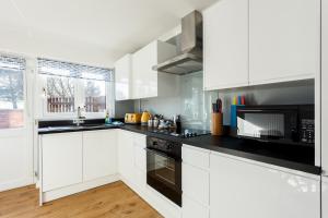 a kitchen with white cabinets and black appliances at Fantasea in Poole