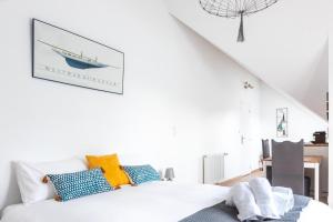 a white bedroom with a bed with blue and yellow pillows at Les Vestiges du jour in Clohars-Fouesnant