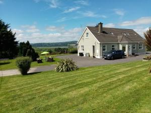 a white house with a car parked in the driveway at Daleview House in Manorcunningham