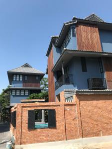 een gebouw met twee verdiepingen en een stenen muur bij P.O.E Posh Homestay in Cha Am