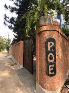 een stenen muur met een bord naast een hek bij P.O.E Posh Homestay in Cha Am