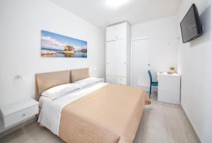 a white bedroom with a bed and a tv at B&B La Gioia in Ischia