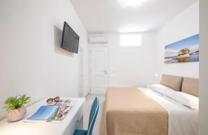 a small white room with a bed and a tv at B&B La Gioia in Ischia