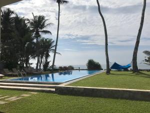 a swimming pool with palm trees and the ocean at Silverlane Beach House in Matara
