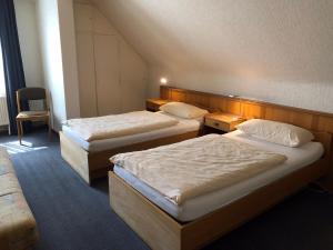 a hotel room with two beds and a chair at Hotel Cao in Hemmingen