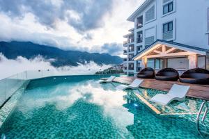 a hotel swimming pool with chairs and mountains in the background at Bamboo Sapa Hotel in Sapa