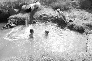 a group of three children playing in a pond at Healing Hands in Merom Golan