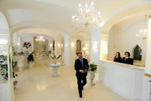 Ein Mann im Anzug, der durch eine große Lobby geht. in der Unterkunft Minori Palace in Minori