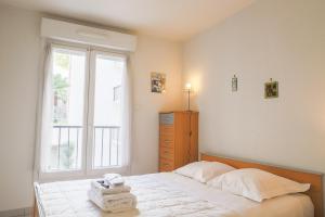 een slaapkamer met een bed met witte lakens en een raam bij CANNES Palazzio in Cannes