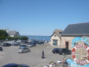 un estacionamiento con autos estacionados frente a un edificio en hotel de la plage, en Piriac-sur-Mer