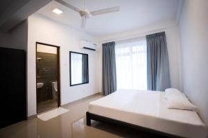 a bedroom with a white bed and a large window at Kozy B&B in Mount Lavinia