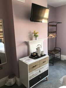 a bedroom with a dresser with a tv on the wall at Mad O'Rourkes Pie Factory in Dudley